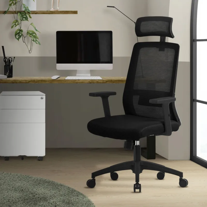 Schwarzer Bürostuhl vor einem Schreibtisch mit Computer und Pflanzen im Hintergrund.