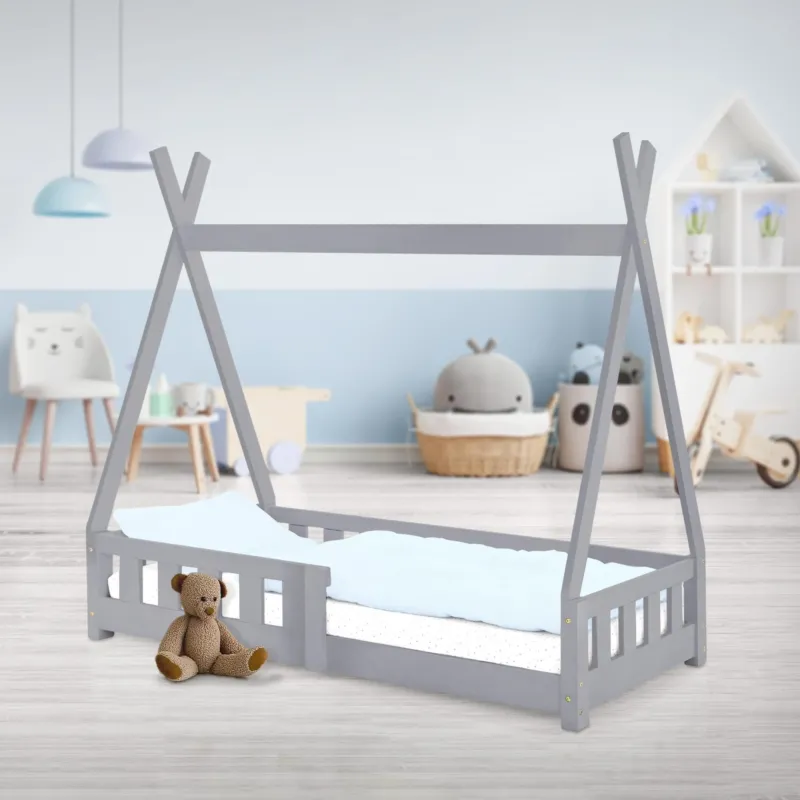 Hellgraues Kinderbett mit einem Teddybär und einem hellen Raum im Hintergrund.